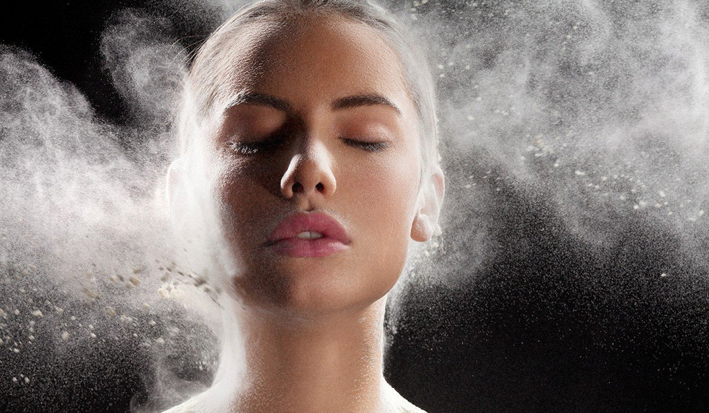 Female with eyes closed and cloud of white mist spray surrounding face.